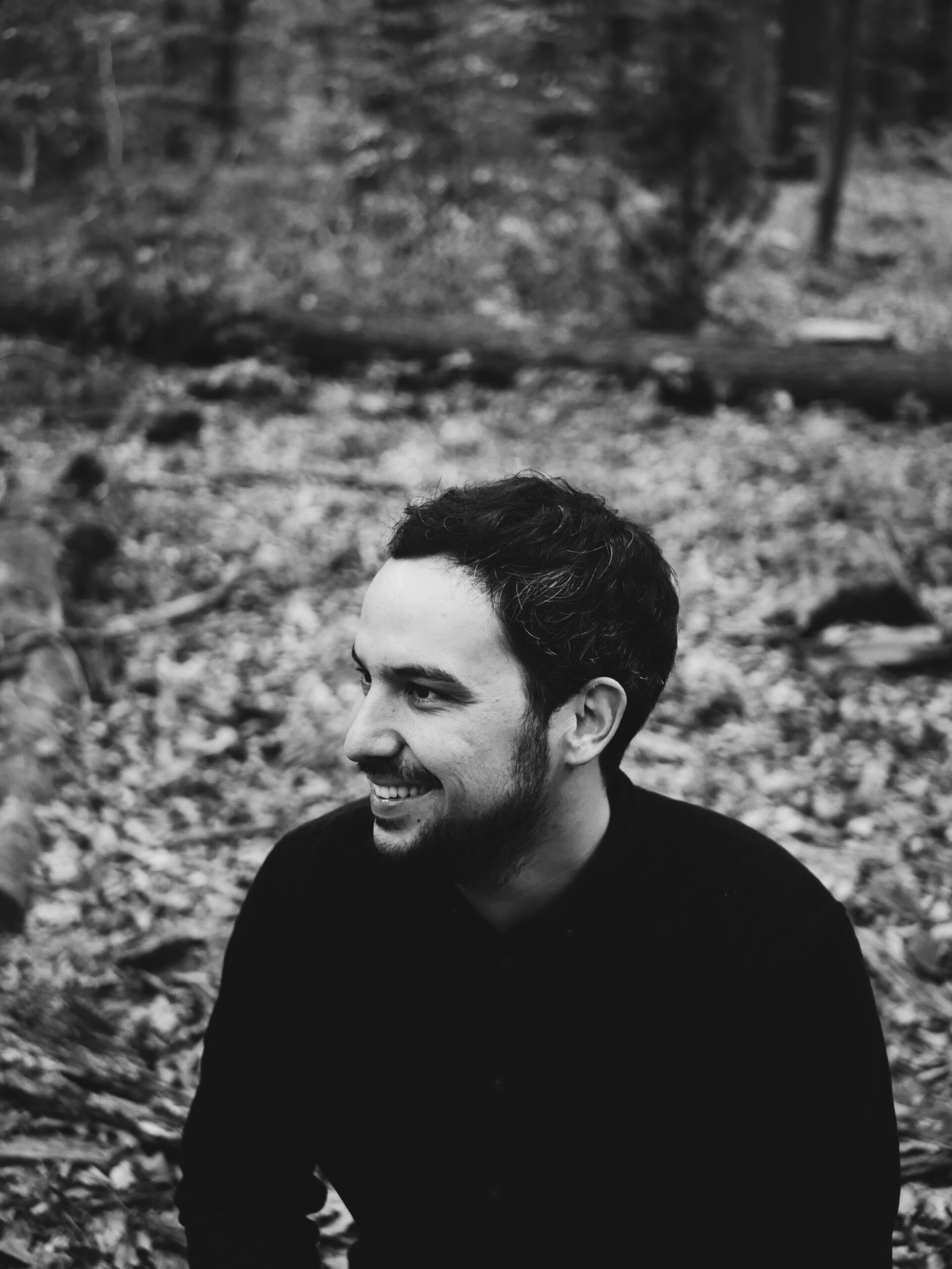 Auf dem Foto ist der Stuttgarter Sänger-Songwriter Nasim zu sehen. Hinter ihm ist ein Wald. Das Foto ist ein schwarzweiß Bild.